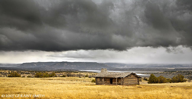 Log cabin, Abiquiu Lake and approaching spring storm from Ghost Ranch, New Mexico