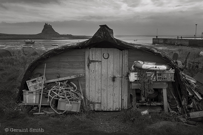Over turned boat storage shed on the Holy Island of Lindisfarne castle uk great britain